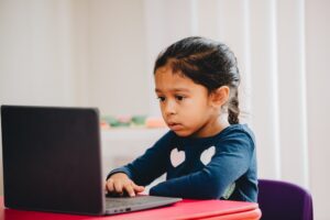 diverse pre-k girl at home on computer doing online schooling or e-learning, early education