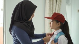 young mother helping elementary school children fix ties who are going to school